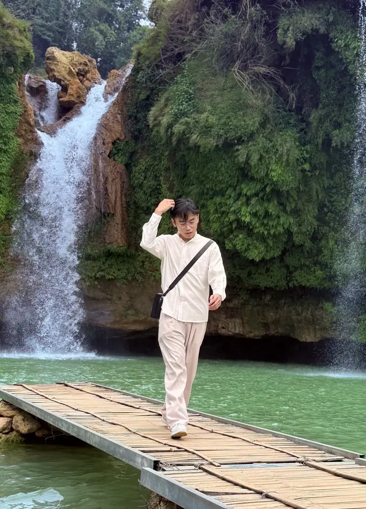 Hung walking on a wooden dock toward a waterfall