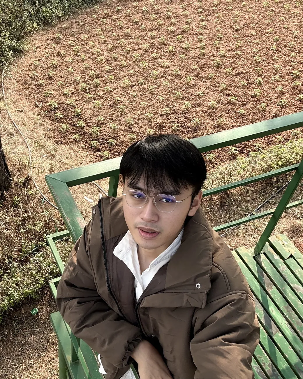 Hung sitting outdoors in a brown jacket
